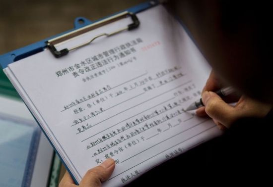 于娟和同事正在协作登记商贩的营业执照。